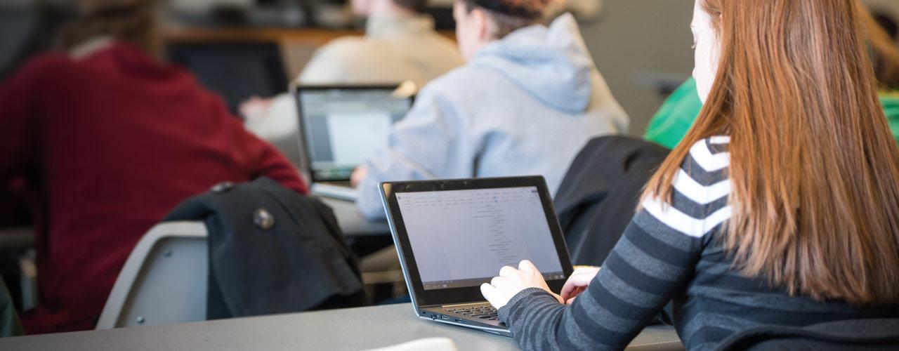 Female student takes notes on laptop in class